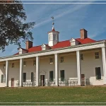 A historic building with a red roof and white columns, set against a clear blue sky.