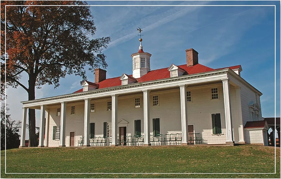 A historic building with a red roof and white columns, set against a clear blue sky.